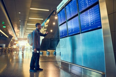 Photo for There are many flights today. a young man looking at a board in an airport - Royalty Free Image