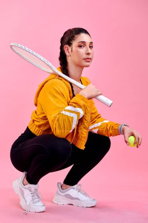 Foto de Mantén la calma fuerte. Retrato de estudio de una joven deportista posando con una raqueta de tenis y pelota sobre un fondo rosa - Imagen libre de derechos