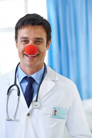 Photo for Laughter is the best medicine. Portrait of a handsome smiling young doctor wearing a red clown nose - Royalty Free Image