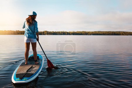 Photo for Out exploring the waters. a young woman paddle boarding on a lake - Royalty Free Image