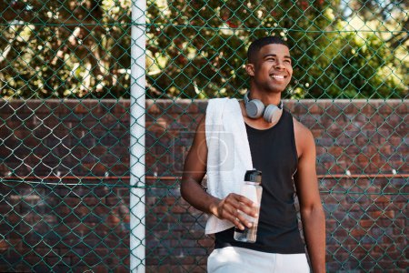Photo for Be optimistic about what youre able to achieve. a sporty young man taking a break while standing against a fence outdoors - Royalty Free Image