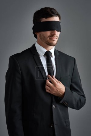 Foto de Is your lack of vision limiting you. Studio shot of a young businessman wearing a blindfold against a gray background - Imagen libre de derechos