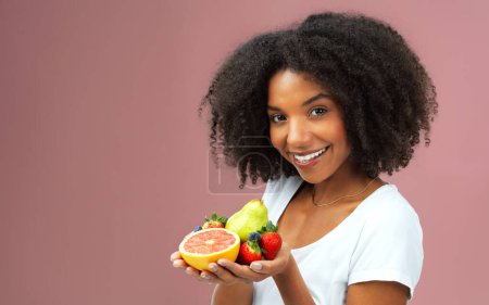 Photo for Who needs candy when youve got these. Studio shot of an attractive young woman holding fruit against a pink background - Royalty Free Image
