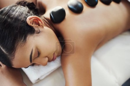 Photo for Woman, relax and sleeping in rock massage at spa for skincare, beauty or body treatment at salon. Calm female asleep with eyes closed and hot rocks on back for healthy physical therapy at the resort. - Royalty Free Image
