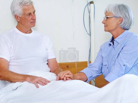 Téléchargez les photos : Voir ça ensemble. un malade dans un lit d'hôpital réconforté par sa femme - en image libre de droit
