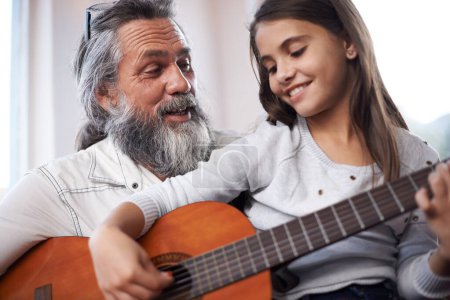 Téléchargez les photos : Fille avec grand-père, heureuse avec la guitare et apprendre à jouer, l'éducation musicale et le développement créatif. Musicien, art et vieil homme aidant les jeunes filles à apprendre la concentration et l'habileté sur l'instrument de musique. - en image libre de droit