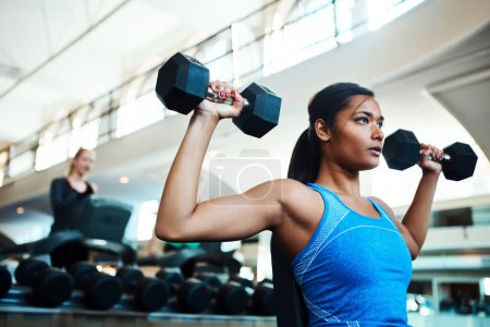 Foto de Pon la barra más alta. una atractiva joven haciendo ejercicio con pesas en el gimnasio - Imagen libre de derechos