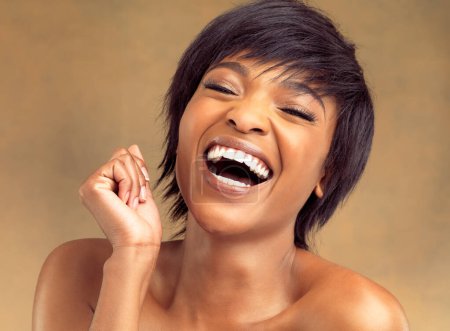 Foto de La risa es hermosa. Retrato de estudio de una hermosa joven riendo sobre un fondo marrón - Imagen libre de derechos