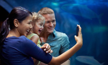 Aquarium, glückliche und familiäre Selfies von Fischen im Urlaub, Urlaub und gemeinsame Ausflüge. Foto, Fischbecken und Vater, Mutter und Mädchen beim Fotografieren für das Gedächtnis, soziale Medien oder Profilbild im Ozeanarium.