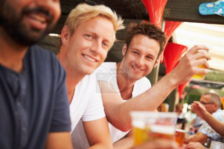 Téléchargez les photos : Croustillant et savoureux. Les jeunes hommes s'appuient contre le bar en dégustant des bières lors d'un festival de musique - en image libre de droit