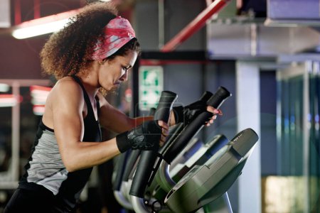 Téléchargez les photos : Elle se dirige vers la forme physique. une jeune femme travaillant avec une machine à pas à la salle de gym - en image libre de droit