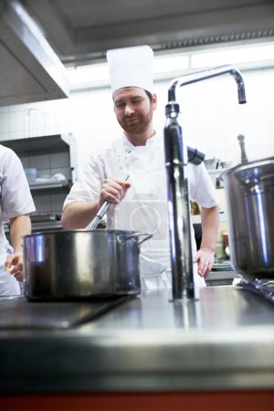 Téléchargez les photos : C'est un habile saucier. chefs préparant un service de repas dans une cuisine professionnelle - en image libre de droit
