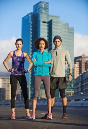 Téléchargez les photos : Sérieusement prêt à courir. trois jeunes joggeurs debout dans une route vide dans la ville - en image libre de droit