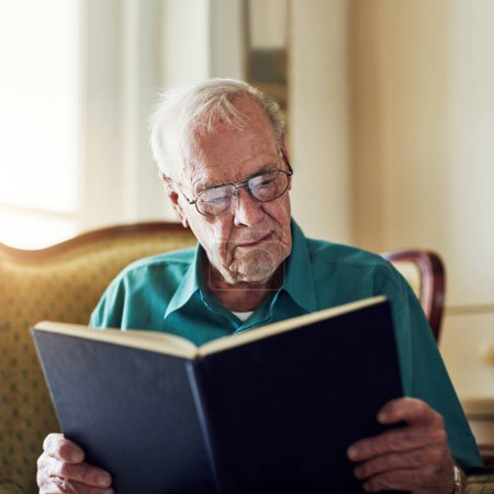Foto de Nunca perdió el interés en la lectura. un hombre mayor leyendo un libro mientras se relaja en casa - Imagen libre de derechos