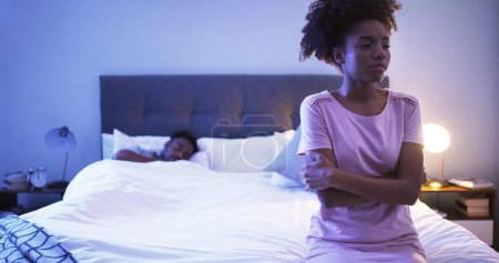Photo for Black couple, bedroom and night with a woman sad while thinking of divorce, stress or depression. Man sleeping in home bed with partner upset about fight, marriage problem and cheating or infertility. - Royalty Free Image