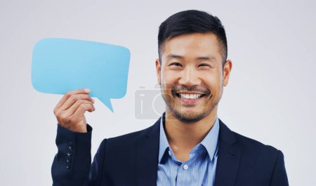 Foto de Hombre asiático feliz, retrato y burbuja del habla para las redes sociales, pregunta o FAQ con sonrisa en un fondo de estudio blanco. Persona masculina emocionada sonriendo con signo de comentario, mensaje o espacio de maqueta. - Imagen libre de derechos
