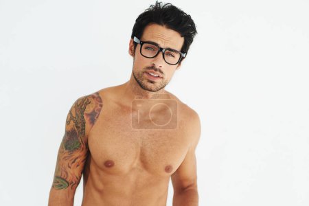 Photo for Portrait, topless and glasses with a sexy man model in studio on a white background for masculine strength. Body, tattoo and a handsome young male nerd posing shirtless for muscular confidence. - Royalty Free Image