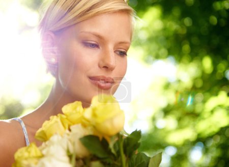 Téléchargez les photos : Une beauté délicate. une jeune femme souriante debout dehors tenant un bouquet de roses jaunes - en image libre de droit