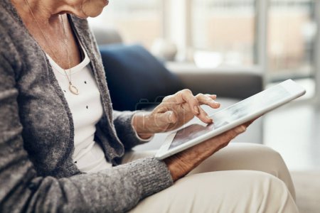 Téléchargez les photos : Il y a quelque chose pour tout le monde en ligne. une femme âgée utilisant une tablette numérique tout en se relaxant à la maison - en image libre de droit