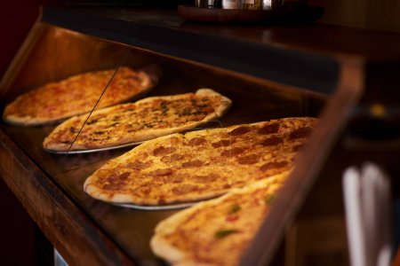 Foto de Tenemos una variedad para elegir. Primer plano de pizza en exhibición en un café - Imagen libre de derechos