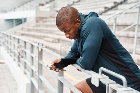 Téléchargez les photos : Je consulte mes réseaux sociaux. un beau jeune athlète debout seul et envoyant des SMS sur son téléphone portable après une séance d'entraînement en plein air - en image libre de droit