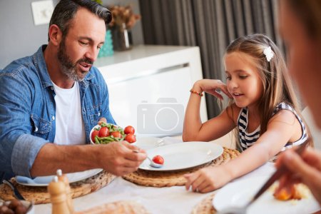 Téléchargez les photos : Je sais que tu aimes tes tomates. une jeune famille se tenant la main dans la prière avant de prendre un repas ensemble à la maison - en image libre de droit
