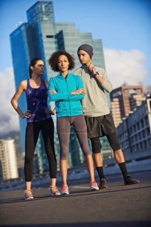 Téléchargez les photos : Sérieusement prêt pour une course. Portrait de trois jeunes joggeurs debout dans une rue vide de la ville - en image libre de droit
