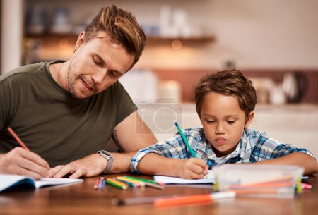 Foto de Ambos tenemos tarea que hacer. un hombre sentado con su hijo mientras hace su tarea - Imagen libre de derechos