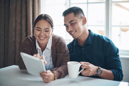 Photo for Theres so much trending online today. a young couple using a digital tablet together at home - Royalty Free Image