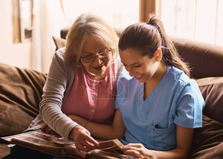 Photo for Stimulating memories through photographs. a nurse and a senior woman looking at a photo album together - Royalty Free Image