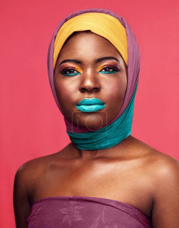 Foto de Maquillaje audaz, envoltura y retrato de una mujer negra aislada sobre un fondo rosa en un estudio. Brillante, color y foto de un modelo africano con sombreros y cosméticos para la cultura y el estilo de vida. - Imagen libre de derechos