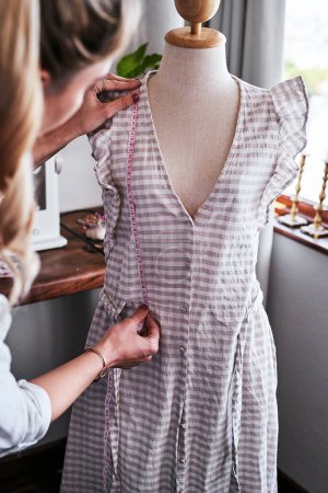 Téléchargez les photos : Cette robe est parfaite pour la femme moderne. un jeune créateur de mode travaillant sur un vêtement suspendu sur un mannequin - en image libre de droit