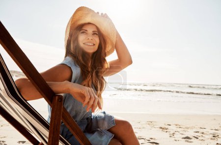 Téléchargez les photos : La plage est certainement un endroit magique à être. une jeune femme se relaxant sur une chaise longue à la plage - en image libre de droit