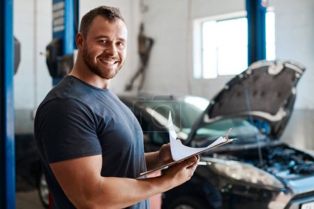 Photo for With the right mindset, you can achieve anything. a mechanic holding a clipboard while working in an auto repair shop - Royalty Free Image