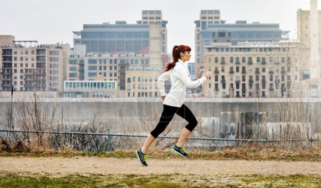 Foto de Es hora de reinventar tu cuerpo. una joven deportista corriendo junto a la ciudad - Imagen libre de derechos