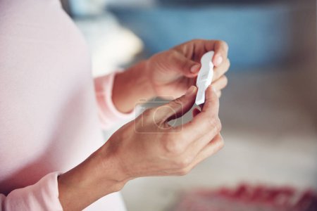 Closeup, hand and woman with a pregnancy test, waiting for the results and wellness at home. Zoom, female person and lady with expectation, pregnant and future maternity with fertility treatment.