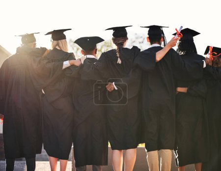 Photo for Reaching a great milestone in their lives. Rearview shot of a group of university students standing outside on graduation day - Royalty Free Image