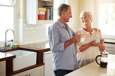 Photo for Happy, coffee or old couple laughing in kitchen at home bonding or enjoying quality morning time together. Funny, affection or mature man talking, relaxing or drinking tea espresso with woman at home. - Royalty Free Image