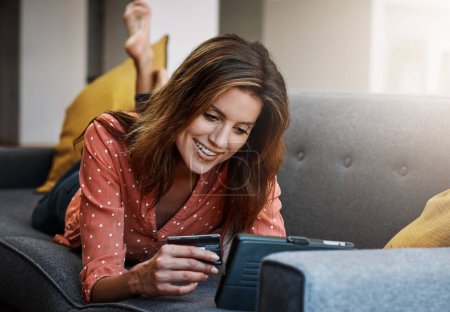 Photo for Convenience and comfort, courtesy of credit. an attractive young woman using a digital tablet and credit card on the sofa at home - Royalty Free Image