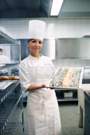 Photo for Master of the art of sushi making. Portrait of a chef holding a large platter of sushi in a restaurant kitchen - Royalty Free Image