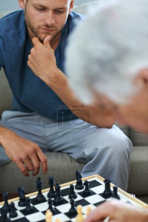 Téléchargez les photos : Papa a des coups d'échecs intéressants. un père et son fils jouant ensemble à un jeu d'échecs à la maison - en image libre de droit