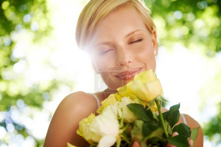 Foto de Toda mujer ama las rosas. una joven sonriente parada afuera sosteniendo un ramo de rosas amarillas - Imagen libre de derechos