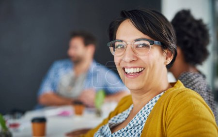 Photo for She makes success look easy. Portrait of a young businesswoman in an office meeting with colleagues in the background - Royalty Free Image