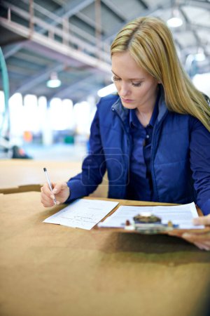 Photo for Shell ensure your shipment is there on time. a woman checking the stock in a warehouse - Royalty Free Image