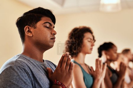 Foto de Ama lo suficiente para cuidar de ti mismo. un grupo de hombres y mujeres jóvenes meditando en una clase de yoga - Imagen libre de derechos