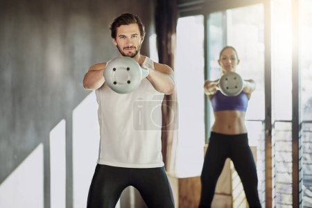 Photo for Swinging to get stronger. two young people working out in the gym using kettle bells - Royalty Free Image