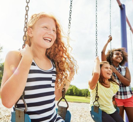Téléchargez les photos : Le bonheur de l'enfance. jeunes filles jouant sur les balançoires au parc - en image libre de droit