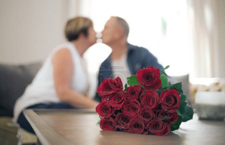 Téléchargez les photos : Tu me fais me sentir tellement aimé. une femme mûre embrassant son mari en remerciement pour les roses - en image libre de droit