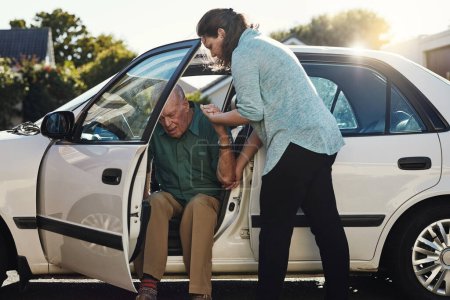 Téléchargez les photos : Laisse-moi t'aider. une femme aidant son père aîné à sortir de la voiture - en image libre de droit