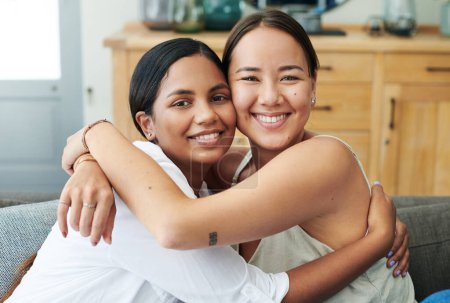 Photo for Shes like my sister. two young women sitting on the sofa together at home and hugging - Royalty Free Image